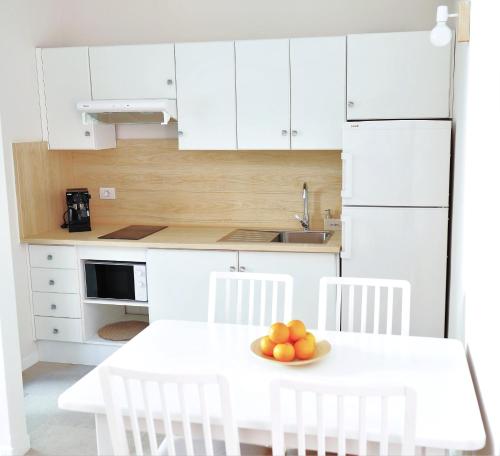 a white kitchen with a table with a bowl of fruit on it at Casa Nature in Playa de Santiago