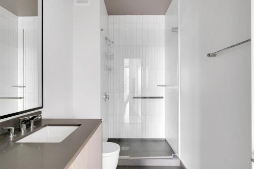 Un baño blanco con lavabo y ducha. en S Loop 2BR w Pool Gym Spa nr Grant Park CHI-740, en Chicago