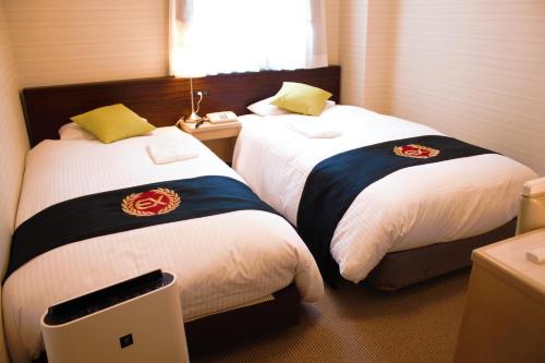 two beds in a hotel room withacers at Grand Park Hotel Excel Kisarazu in Kisarazu