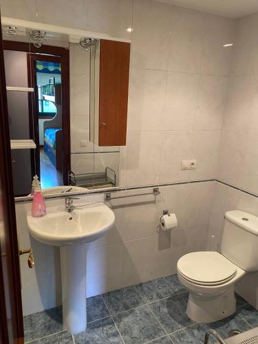 een badkamer met een wastafel, een toilet en een spiegel bij APARTAMENTO LADEIRA PLAYA in Baiona
