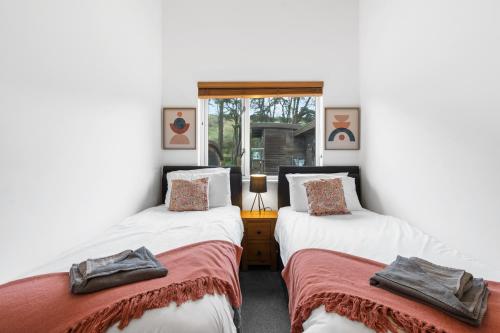 2 Einzelbetten in einem Zimmer mit weißen Wänden in der Unterkunft House 5 Ironcroft - Modern Pet-friendly & hot tub, Walk to beach & village in Porthtowan