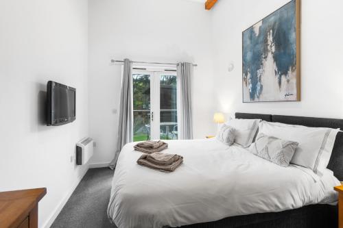 ein weißes Schlafzimmer mit einem Bett mit Handtüchern darauf in der Unterkunft House 5 Ironcroft - Modern Pet-friendly, Walk to beach & village in Porthtowan