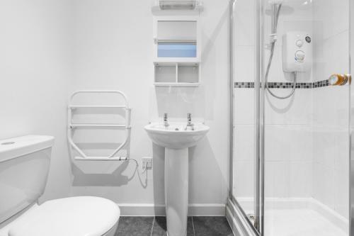 ein weißes Bad mit einer Dusche und einem Waschbecken in der Unterkunft House 5 Ironcroft - Modern Pet-friendly & hot tub, Walk to beach & village in Porthtowan