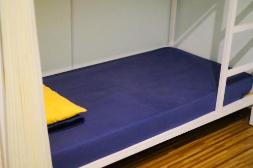 a bunk bed with a blue mattress and a yellow pillow at ROOM Ijen Dormitory & Tours in Banyuwangi