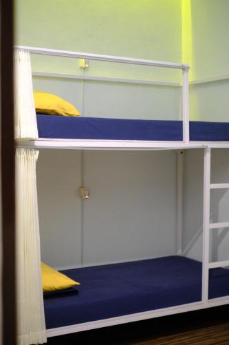 a room with three bunk beds with blue and yellow pillows at ROOM Ijen Dormitory & Tours in Banyuwangi