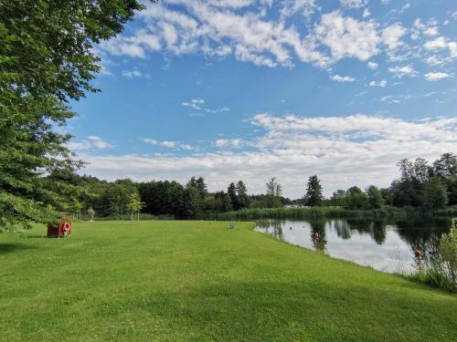 a grassy field with a lake in the middle at Moderne Ferienwohnung Gartenblick in Amtzell
