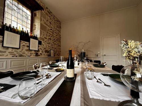 a dining room with a table with a bottle of wine at Le Jardin des Lys in Saint-Léonard-de-Noblat