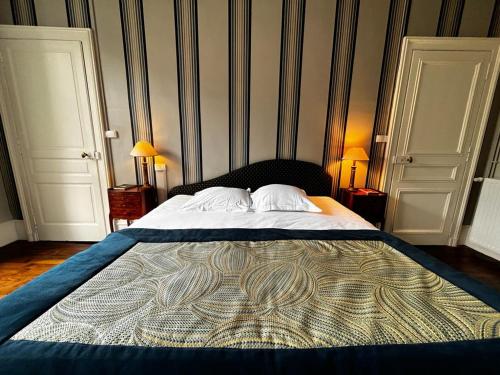 a large bed in a bedroom with two doors at Le Jardin des Lys in Saint-Léonard-de-Noblat