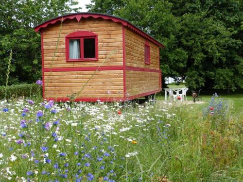 une petite maison en bois dans un champ de fleurs dans l'établissement La roulotte du Leff, à Le Faouët