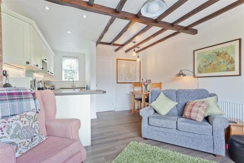 a living room with a couch and a kitchen at Badger's Cottage with stunning lake & mountain views in Coniston
