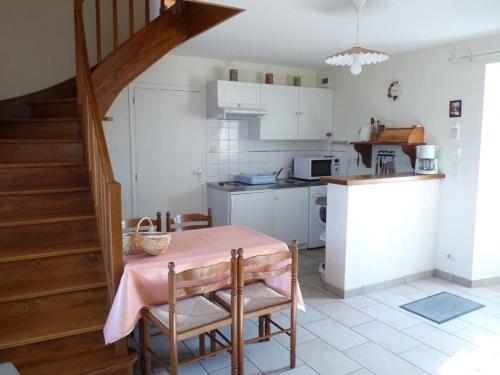 una cocina con mesa y sillas y una escalera en La maison d'angel, en Coussay-les-Bois