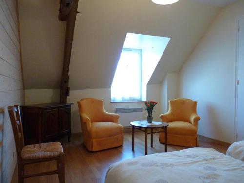 1 dormitorio con 2 sillas, mesa y ventana en La maison d'angel, en Coussay-les-Bois