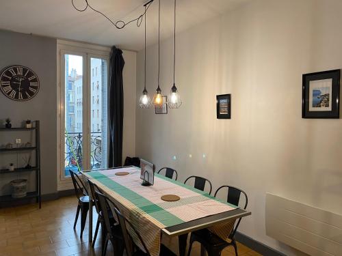 une salle à manger avec une table, des chaises et une horloge dans l'établissement La Plénitude Marseillaise - T4 de 70 m2, 3 chambres, centre-ville, 8 couchages, à Marseille