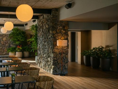 a restaurant with tables and chairs and a stone wall at PACIFIC 19 Kona in Kailua-Kona