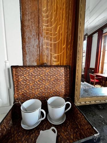 two cups sitting on a table with a mirror at Le Jardin des Lys in Saint-Léonard-de-Noblat