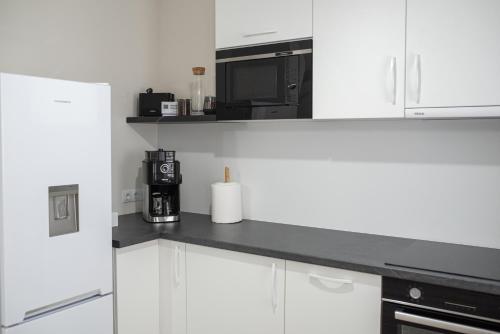 a kitchen with white cabinets and a microwave at TEILOR Apartments 3 in Floreşti