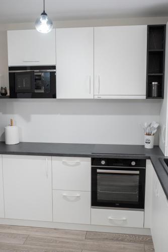 a kitchen with white cabinets and a black oven at TEILOR Apartments 3 in Floreşti