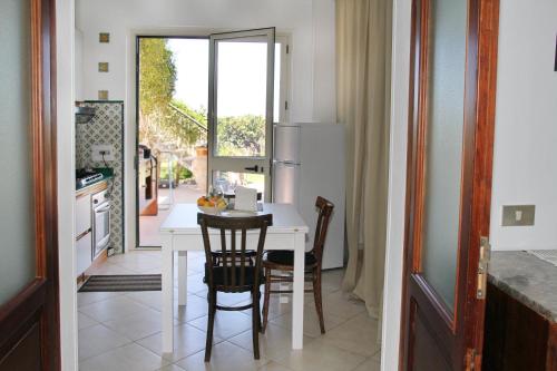 eine Küche mit einem weißen Tisch und Stühlen sowie einem Fenster in der Unterkunft Tenuta Piana 2 con accesso diretto al mare in Caronia