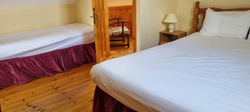 1 dormitorio con 2 camas y 1 silla en Moulamill Cottage, en Gouladane