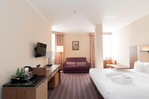 Hotel DeSilva Premium Poznań في بوزنان: غرفه فندقيه بسرير واريكه