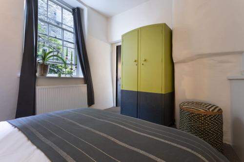a bedroom with a bed and a yellow cabinet at The Colour House Lake District Escape for Two in Kendal