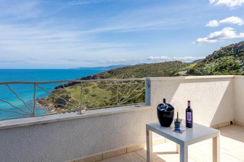 a table with two bottles of wine on a balcony with the ocean at Appartamenti Rocca 'Ja in Castelsardo