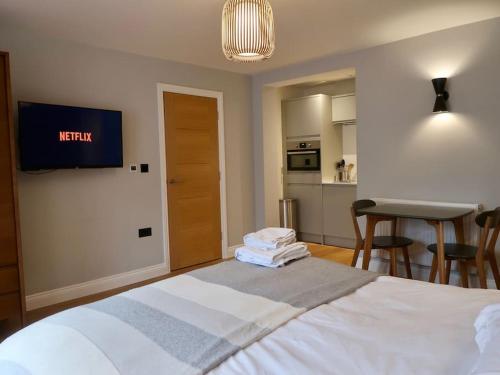 a bedroom with a bed with a tv on the wall at Stylish Studio Apartment, ensuite, kitchenette in Twickenham