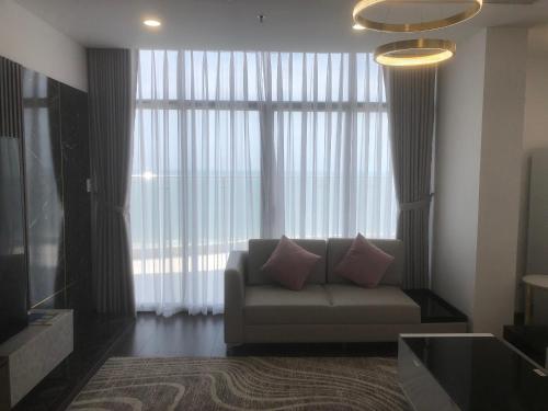 ein Wohnzimmer mit einem Sofa vor einem großen Fenster in der Unterkunft ARIA RESORT-FREE SWIMMING POOL, Relax by sea Hồ bơi miên phí và bãi tắm riêng, 40m ra biển in Vũng Tàu