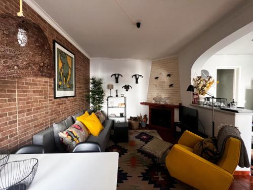 - un salon avec un canapé et un mur en briques dans l'établissement Castelinho da Azóia - Checkinhome, à Sintra