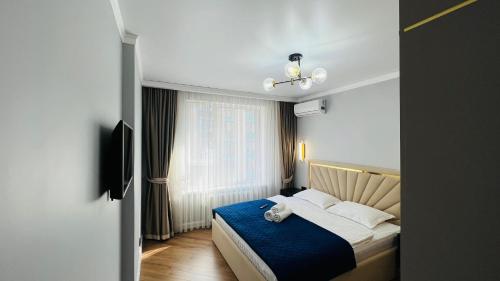 a bedroom with a bed with blue sheets and a window at 2х комнатные апартаменты 4-177 in Almaty