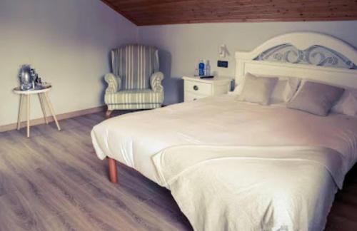 een slaapkamer met een groot wit bed en een stoel bij O Lagoeiro in A Estrada