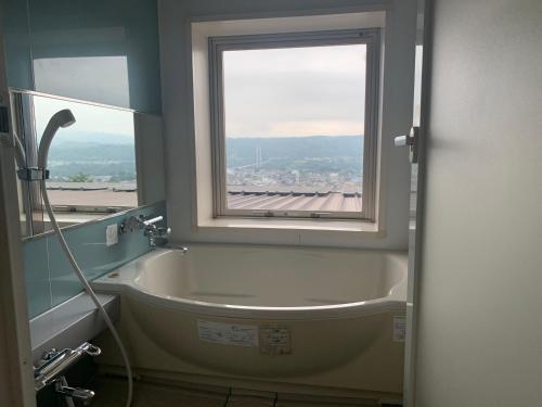 y baño con bañera y ventana. en Natural Farm City Noen Hotel, en Chichibu