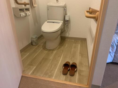 a bathroom with a toilet and a pair of shoes at Natural Farm City Noen Hotel in Chichibu