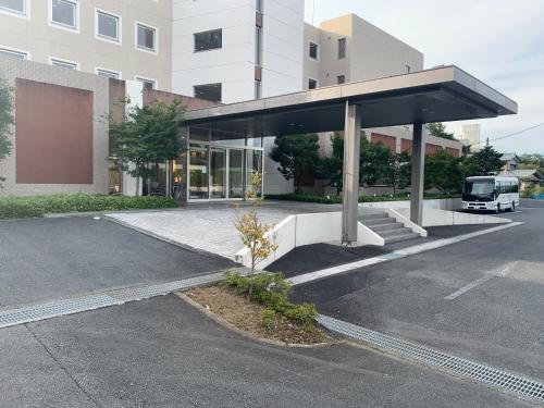 a bus stop in a parking lot next to a building at Natural Farm City Noen Hotel in Chichibu