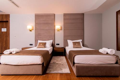 two beds in a room with wooden floors and lights at Deluxe & Executive SPA by Rafaelo in Shëngjin