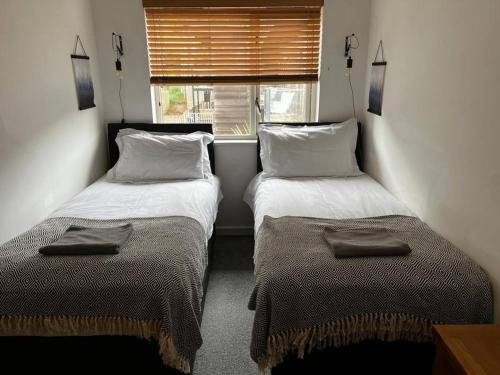 two beds in a small room with a window at House 6 Goldcroft - Walk to Beach & Village, Pet-friendly & hottub in Porthtowan