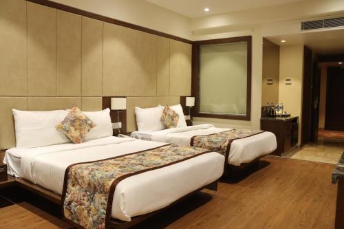 a hotel room with two beds and a mirror at Pride Hotel Bhopal in Bhopal