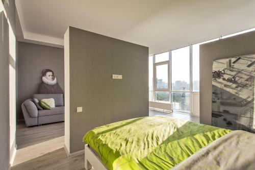 a bedroom with a bed and a woman in a chair at Gagarin Plaza apartment 70 square metres on 12th floor in Odesa