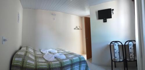 Habitación con cama y TV en la pared. en Suites Pico do Cristal, en Caparaó Velho
