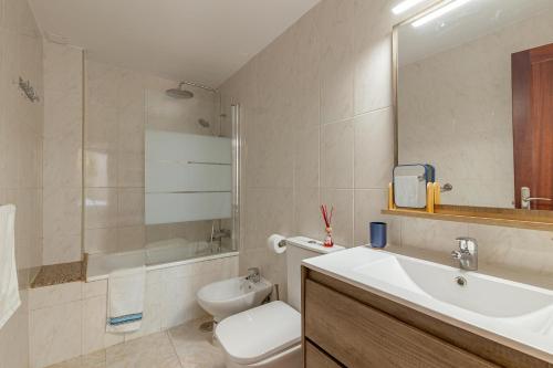 a bathroom with a sink and a toilet and a tub at SeaBliss Beach of Dunes, Terrace and Pool! in San Bartolomé de Tirajana