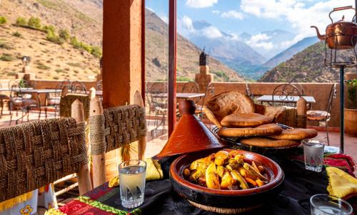 a table with a bowl of bananas and bread on a balcony at Atlas Kasbah Lodge in Imlil