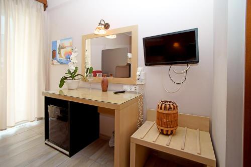 Habitación con escritorio, TV y espejo. en Kyparissia Beach Hotel, en Kyparissia