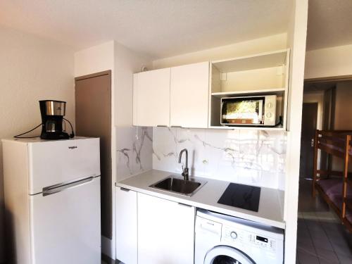 Una cocina con un refrigerador blanco y un fregadero. en Résidence AZUR1 Appartement 251, en Le Lavandou