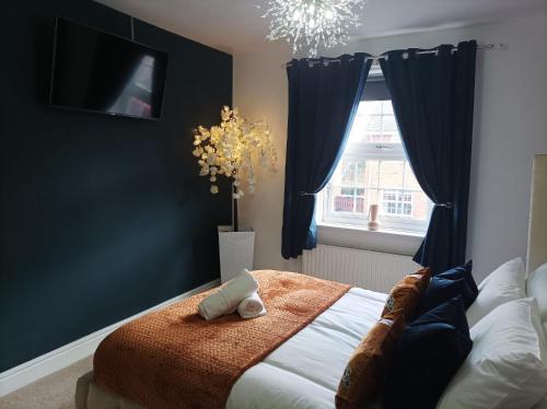 een slaapkamer met een bed met blauwe gordijnen en een raam bij Boutique Abode - With Hot Tub in Chester
