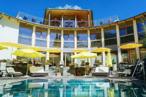 a hotel with a swimming pool and yellow umbrellas at Ortners Eschenhof - Alpine Slowness in Bad Kleinkirchheim