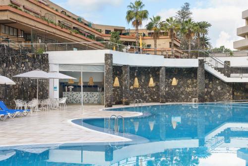 a pool at a hotel with tables and umbrellas at Alua Tenerife in Puerto de la Cruz