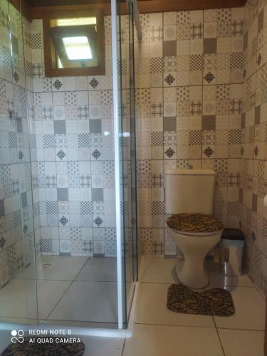 a bathroom with a toilet and a glass shower at Vila Sol Cabana in Lontras