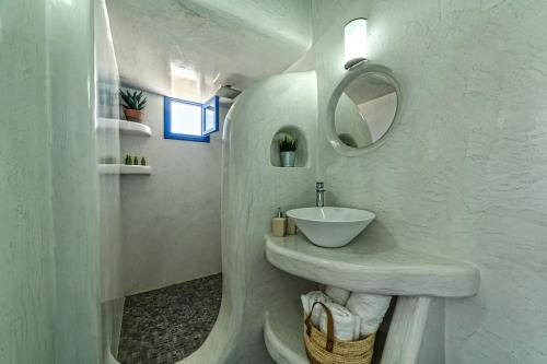 a white bathroom with a sink and a mirror at Elegant Cycladic Villa in Emporio Santorini