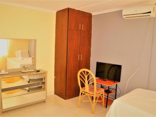 1 dormitorio con escritorio, armario y cama en P Wake Guesthouse, en Opuwo