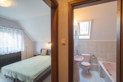 1 dormitorio con cama, lavabo y aseo en Csini vendégház, en Balatonföldvár